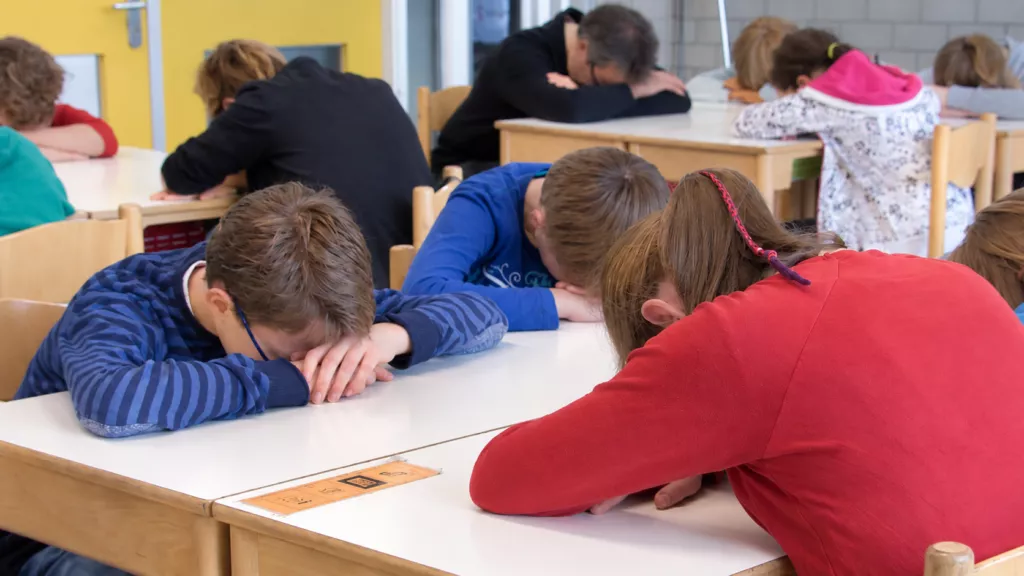 Kinderen in de klas nemen een rustmoment met hun hoofd op hun armen